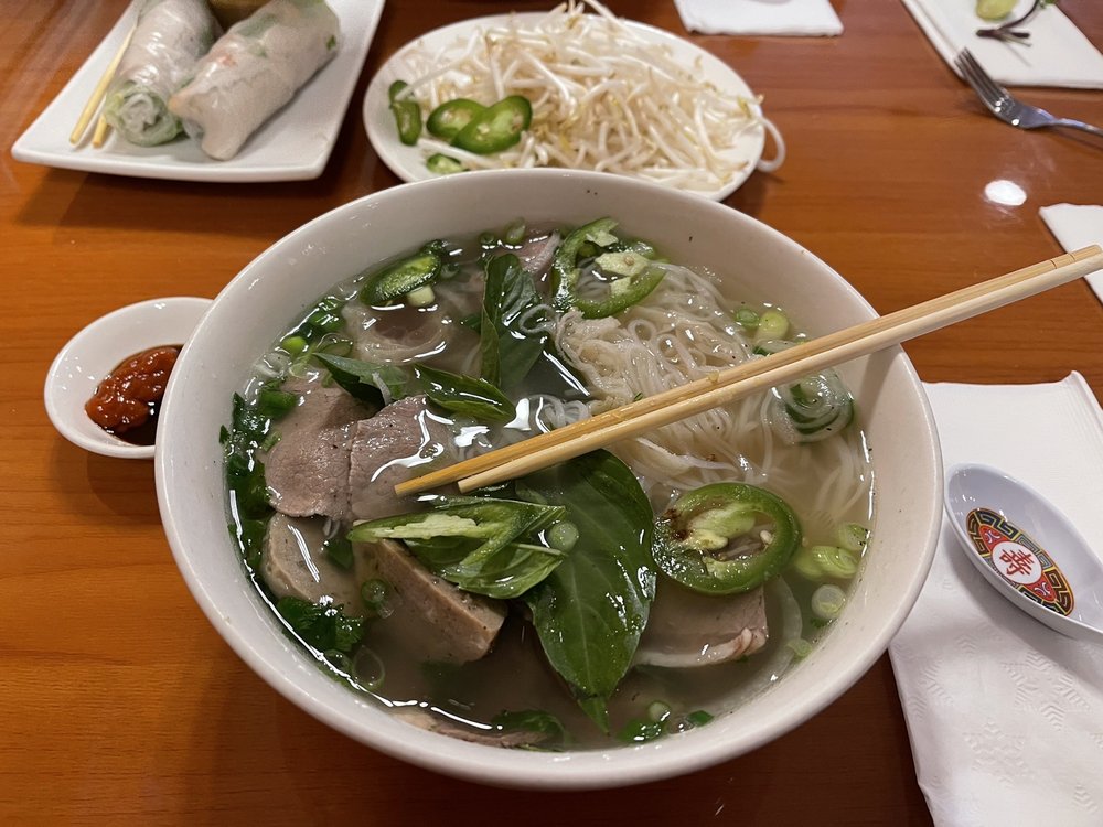 A steaming bowl of beef pho with basil and jalapeño
